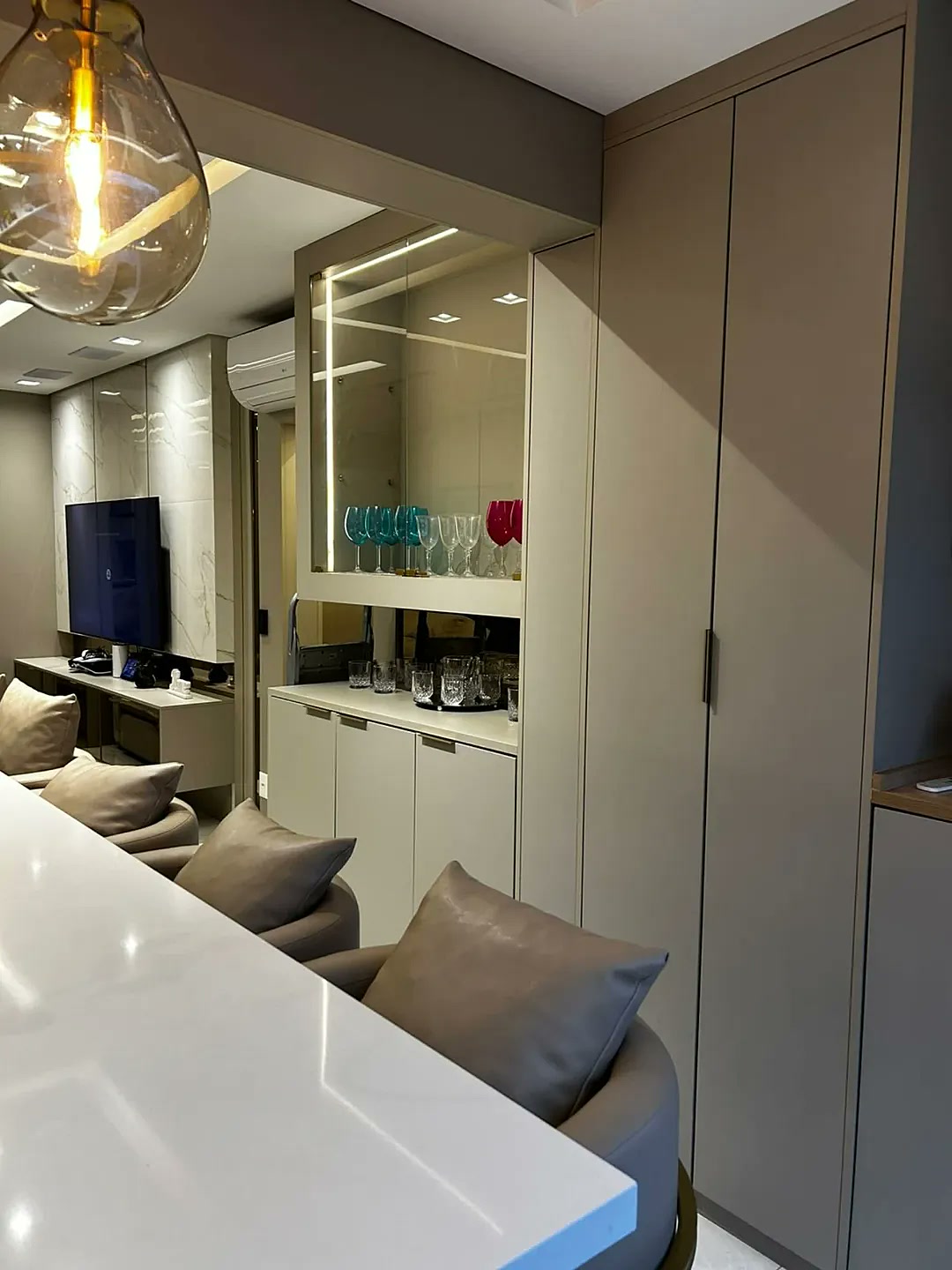 Sala de jantar com cristaleira bar iluminada LED, armário sob medida e taças coloridas – projeto Estillo Design SP