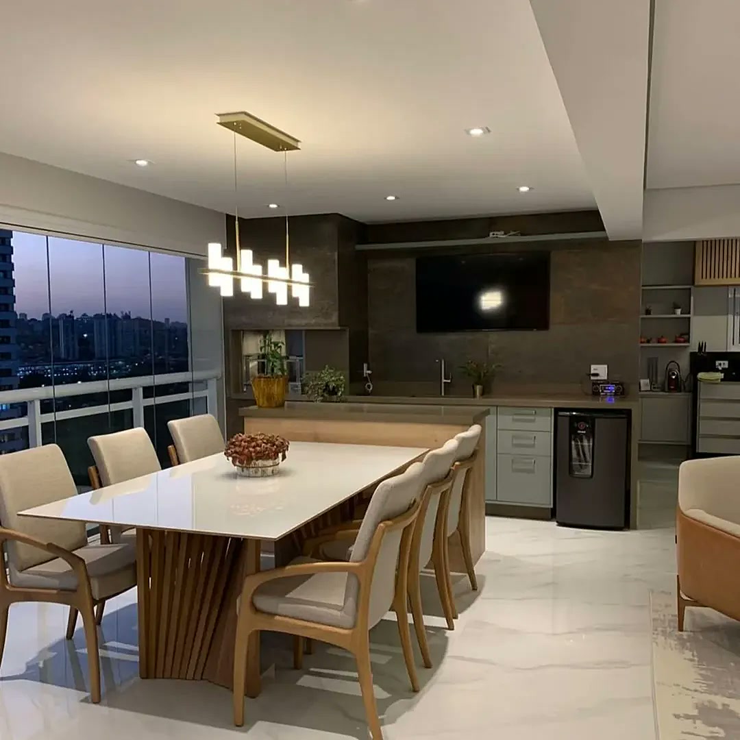 Varanda gourmet planejada com mesa de jantar para 8 lugares, churrasqueira e vista panorâmica de São Paulo – Estillo Design